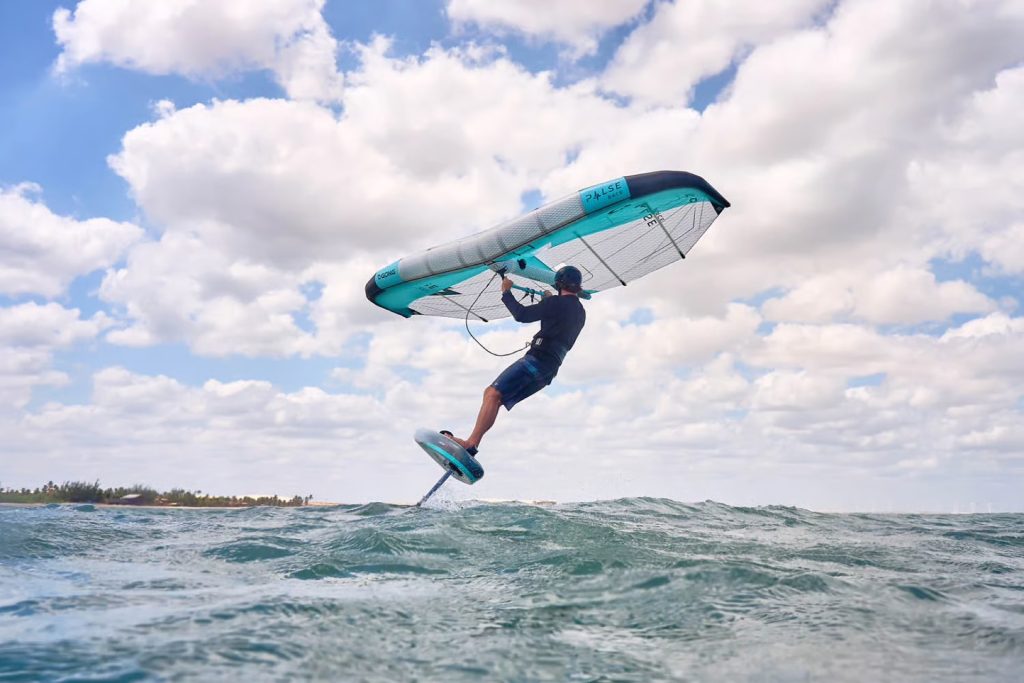 Sportininkas su sparnu skrieja virš jūros, Wind ON – kaitavimo ir wing foil mokykla Svencelėje